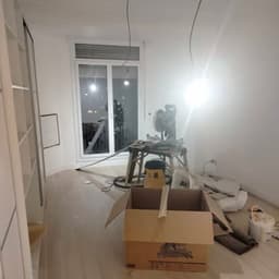 Rénovation intérieure : sol lame aspect bois, scie à onglet sur établi, aspirateur de chantier et placard blanc