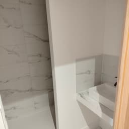 Salle d'eau : douche à l'italienne receveur extra-plat, murs et sol grand format effet marbre blanc veinage gris, vasque à poser rectangulaire et robinetterie noire