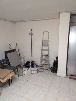 Pièce en rénovation avant création d'une douche : murs nus, sol carrelé clair, échelle et zone technique en préparation