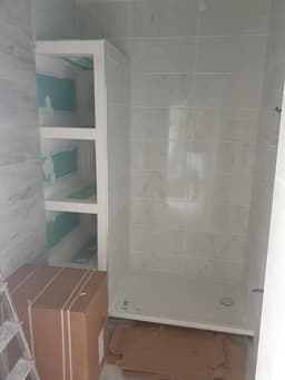 Salle d'eau carrelée en blanc avec niche et réservations sanitaires