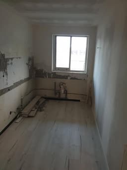Pièce étroite en rénovation avec sol clair posé et murs enduits autour de la fenêtre