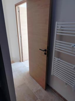 Passage de porte bois avec sol pierre claire et sèche-serviettes visible