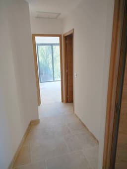 Couloir rénové avec portes bois, murs blancs et sol pierre claire