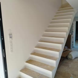 Escalier intérieur avec marches en pierre claire et murs blancs en finition