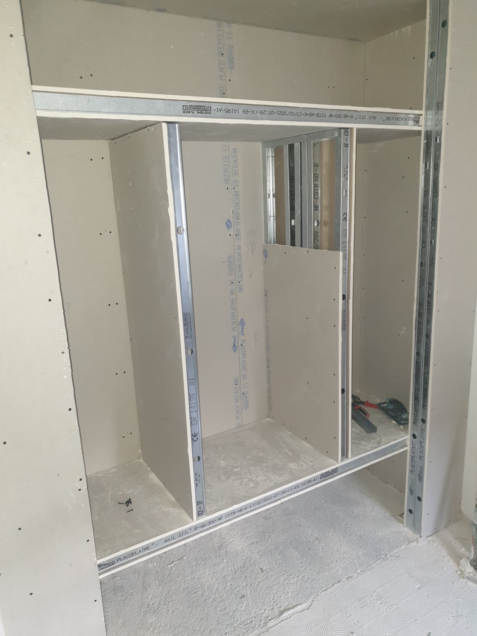 Structure de dressing sur mesure avec rails, montants et cloisons en cours de montage