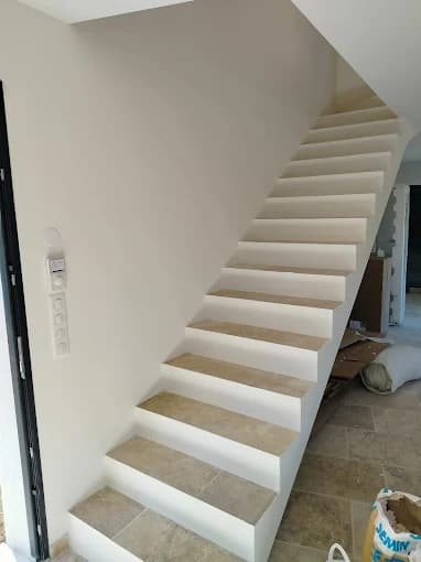 Escalier carrelé pierre claire, contremarches blanches, interrupteurs encastrés
