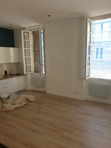 Studio : cuisine blanche, crédence métro, radiateurs sous fenêtres