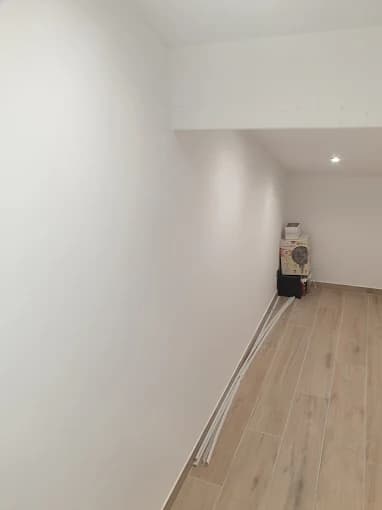 Couloir peint blanc, carrelage aspect bois, pièce vide avant pose des plinthes
