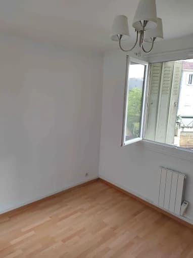 Pièce finie : murs blancs, parquet clair, radiateur et fenêtre
