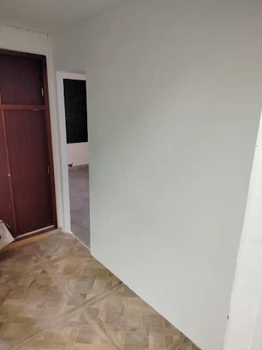 Mur gris uniforme, placard bois foncé, sol carrelé