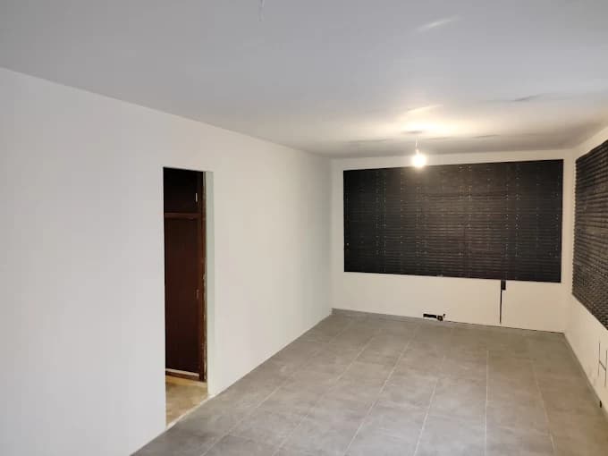 Séjour : murs blancs, panneaux décoratifs noirs, sol carrelé gris