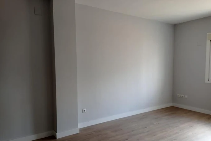 Pièce vide : murs gris, parquet clair, plinthes posées