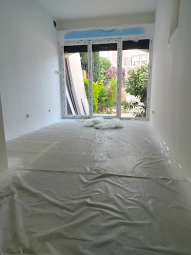 Pièce blanche ouverte sur baies vitrées et jardin