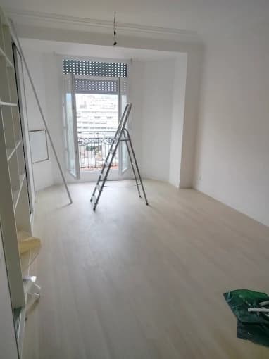 Pièce blanche parquetée, moulures sous plafond (jonction murs-plafond), fenêtres ouvertes sur la ville
