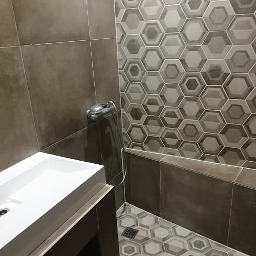 Salle de bain finie : faïence hexagonale et grand format brun, sol carrelé (cadrage mur et sol)