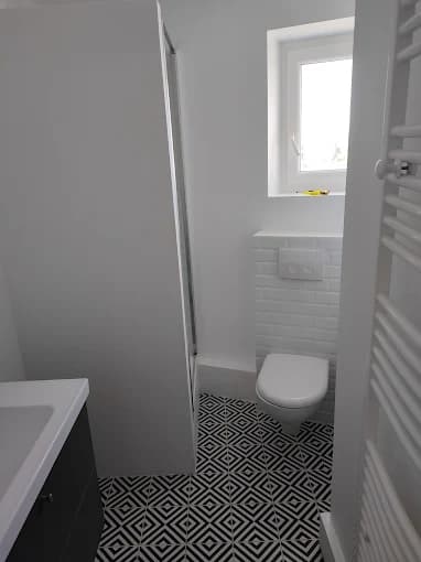 Salle de bain : sol géométrique noir et blanc, faïences (cadrage sans appareils sanitaires visibles)
