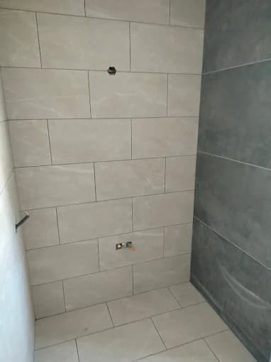 Salle d'eau : carrelage beige et anthracite, réservations robinetterie proprement carrées