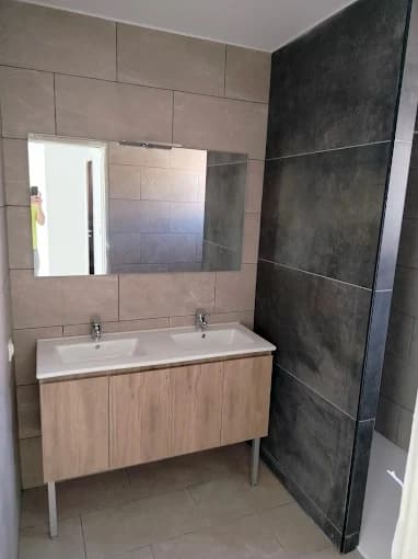 Salle de bain : carrelage mural beige et ardoise, niche et volume bois (vue d’ensemble sans zoom sanitaire)