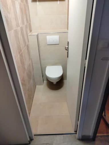 WC : carrelage beige, mur chevron, WC suspendu