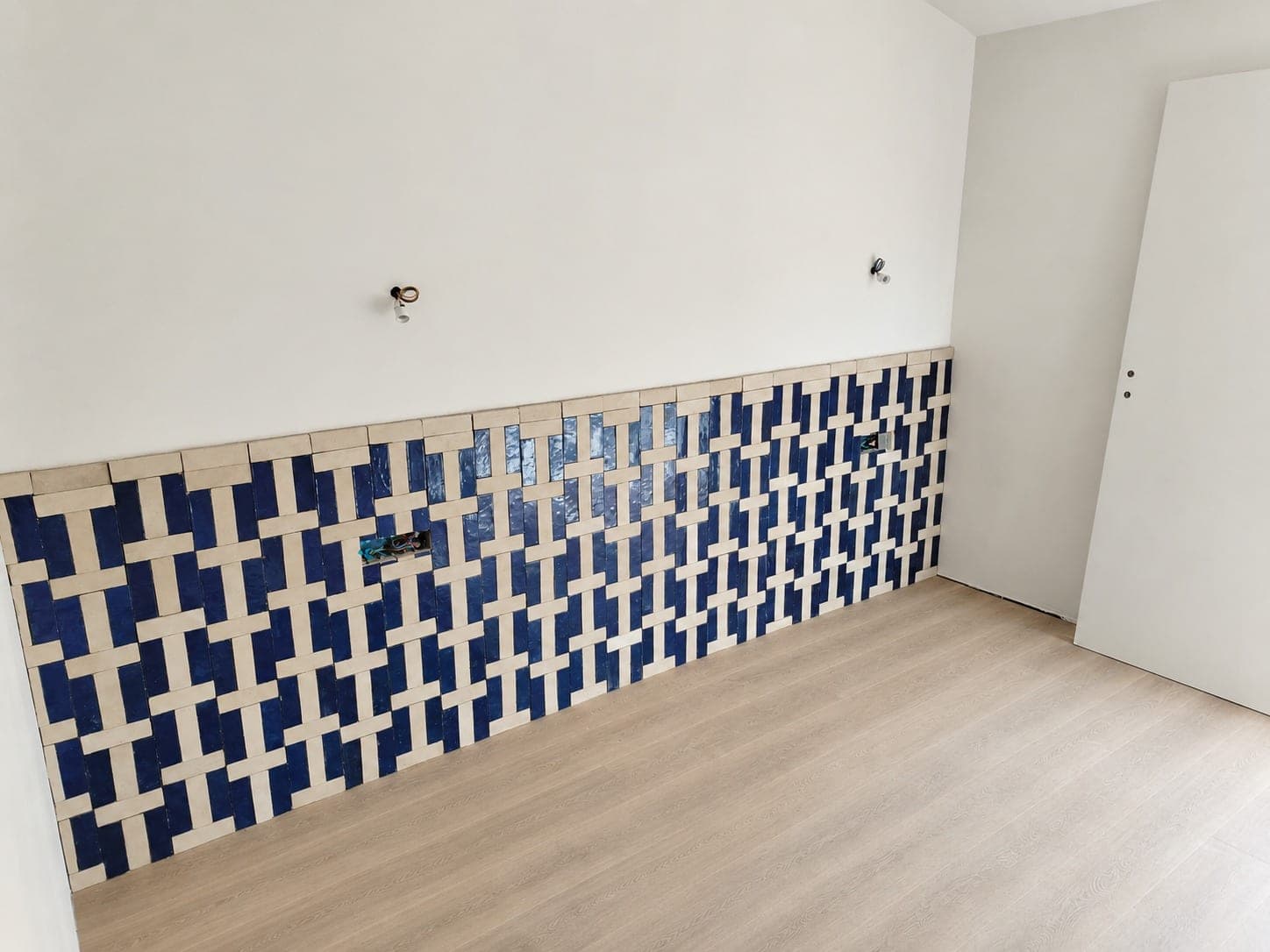 Mur décoratif bleu et blanc en crédence basse avec sol bois clair.