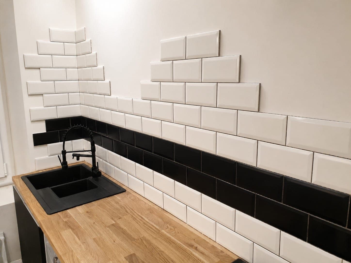 Crédence cuisine en faïence métro blanche avec bande noire.
