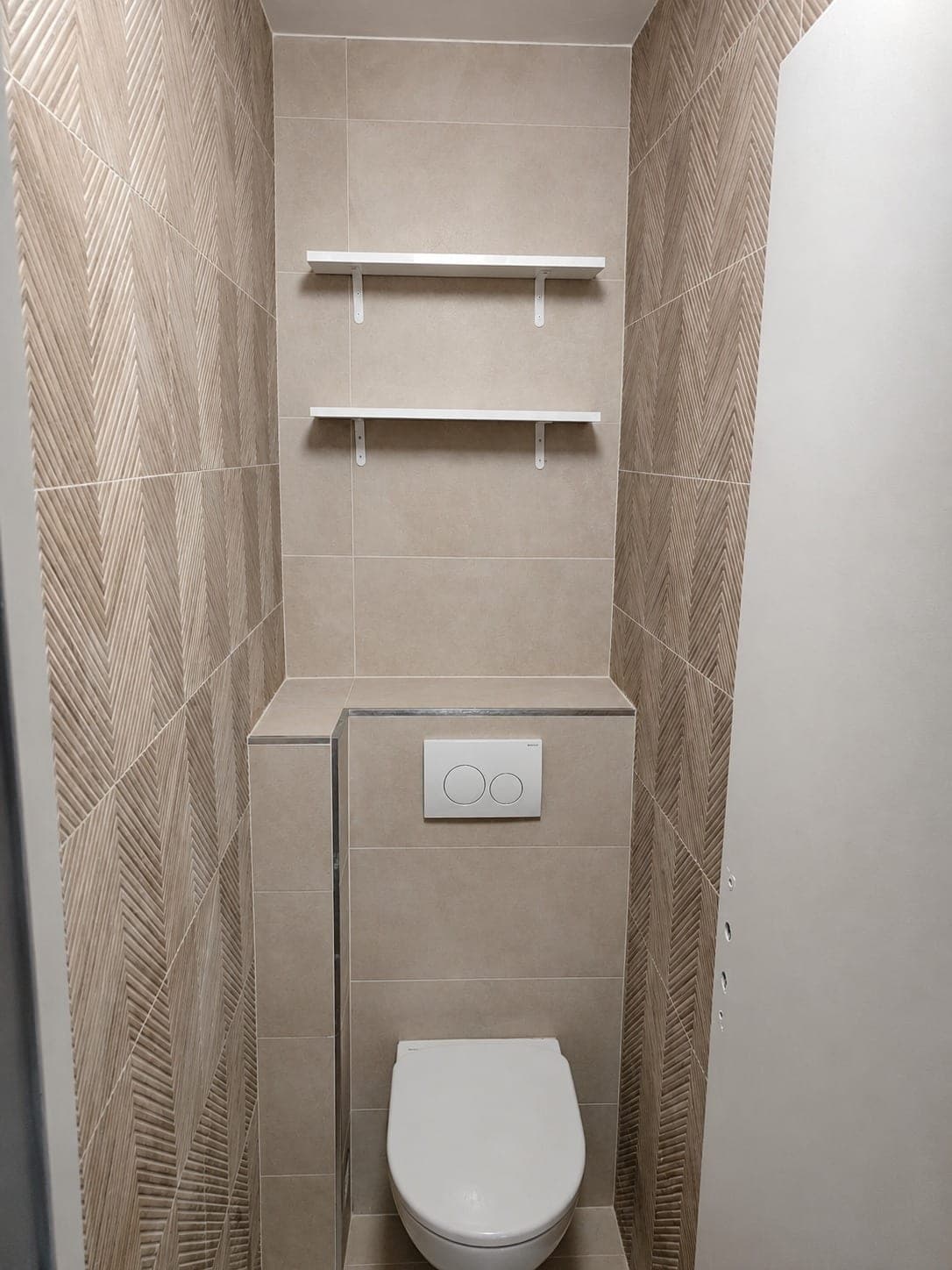 WC suspendu encadré par carrelage mural texturé beige.