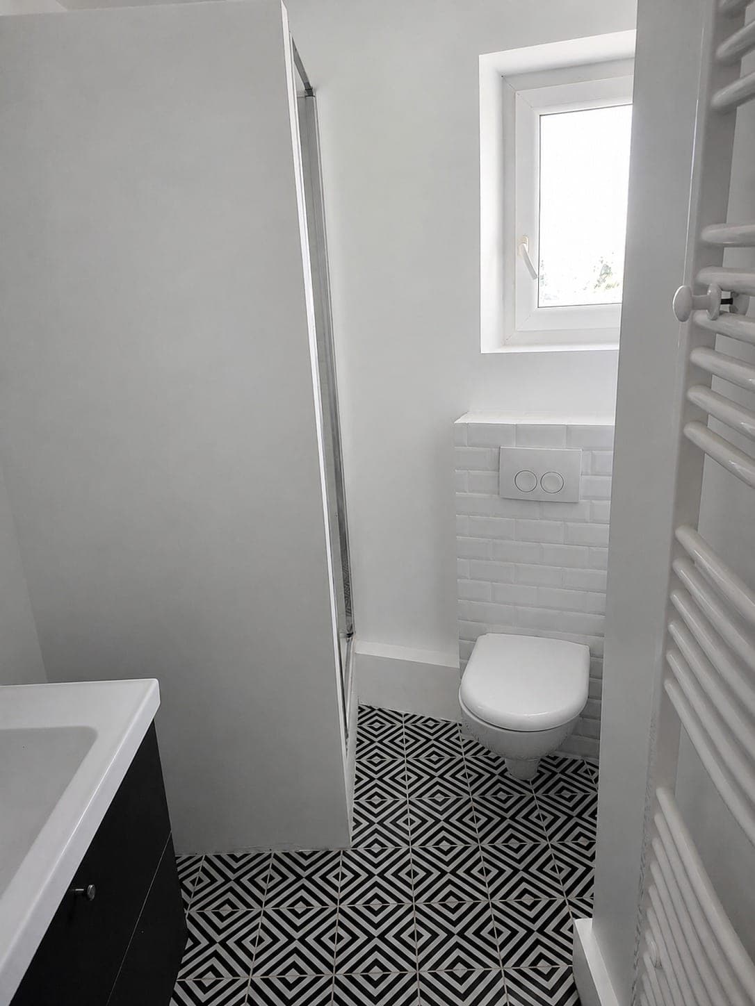 WC avec sol graphique noir et blanc et murs clairs.