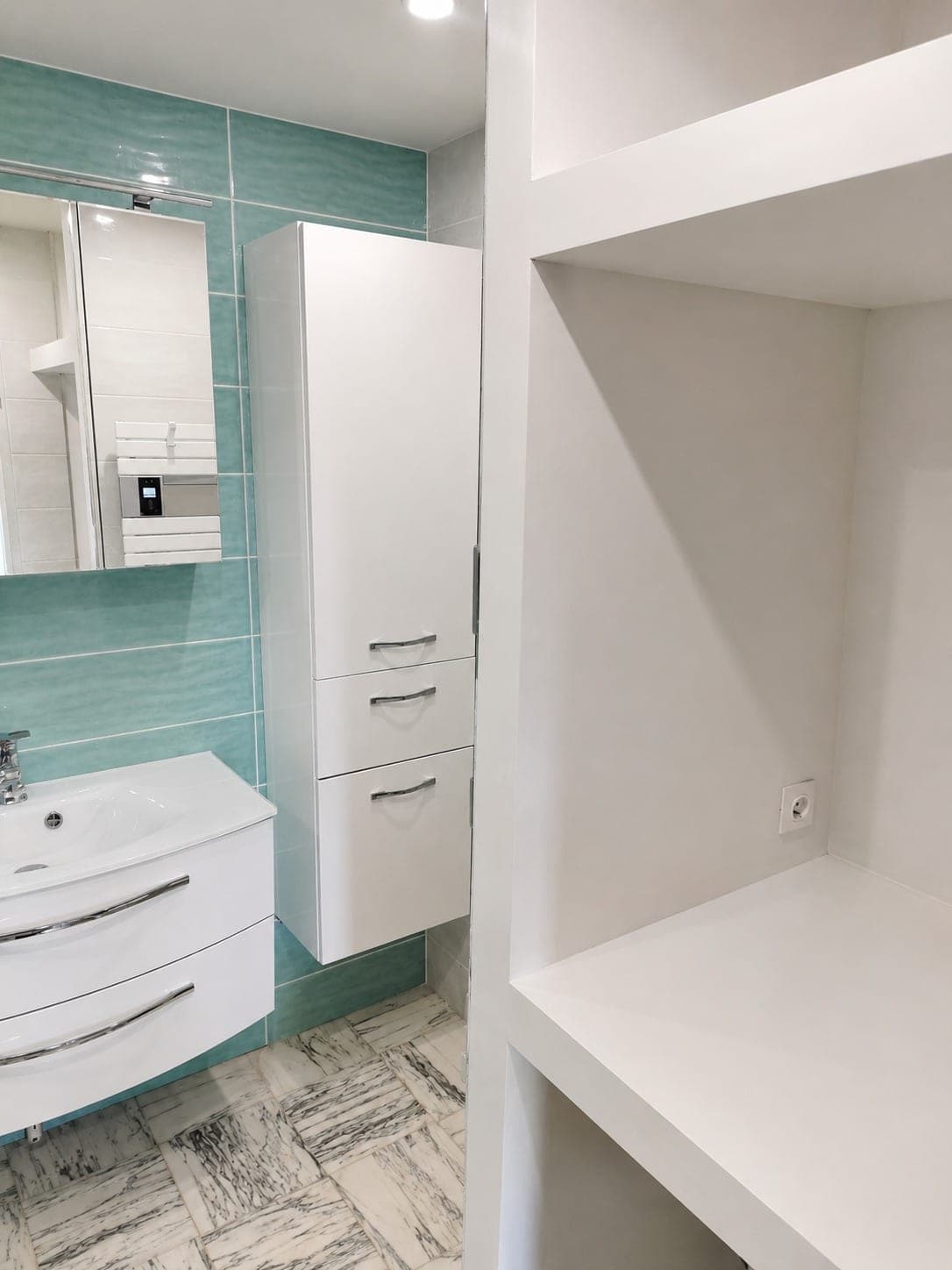 Salle de bain avec faïence verte et sol effet carreaux texturés.
