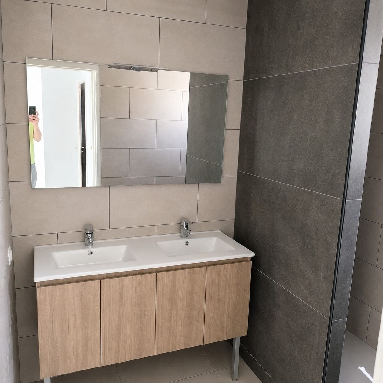 Meuble double vasque devant un ensemble de carreaux gris.