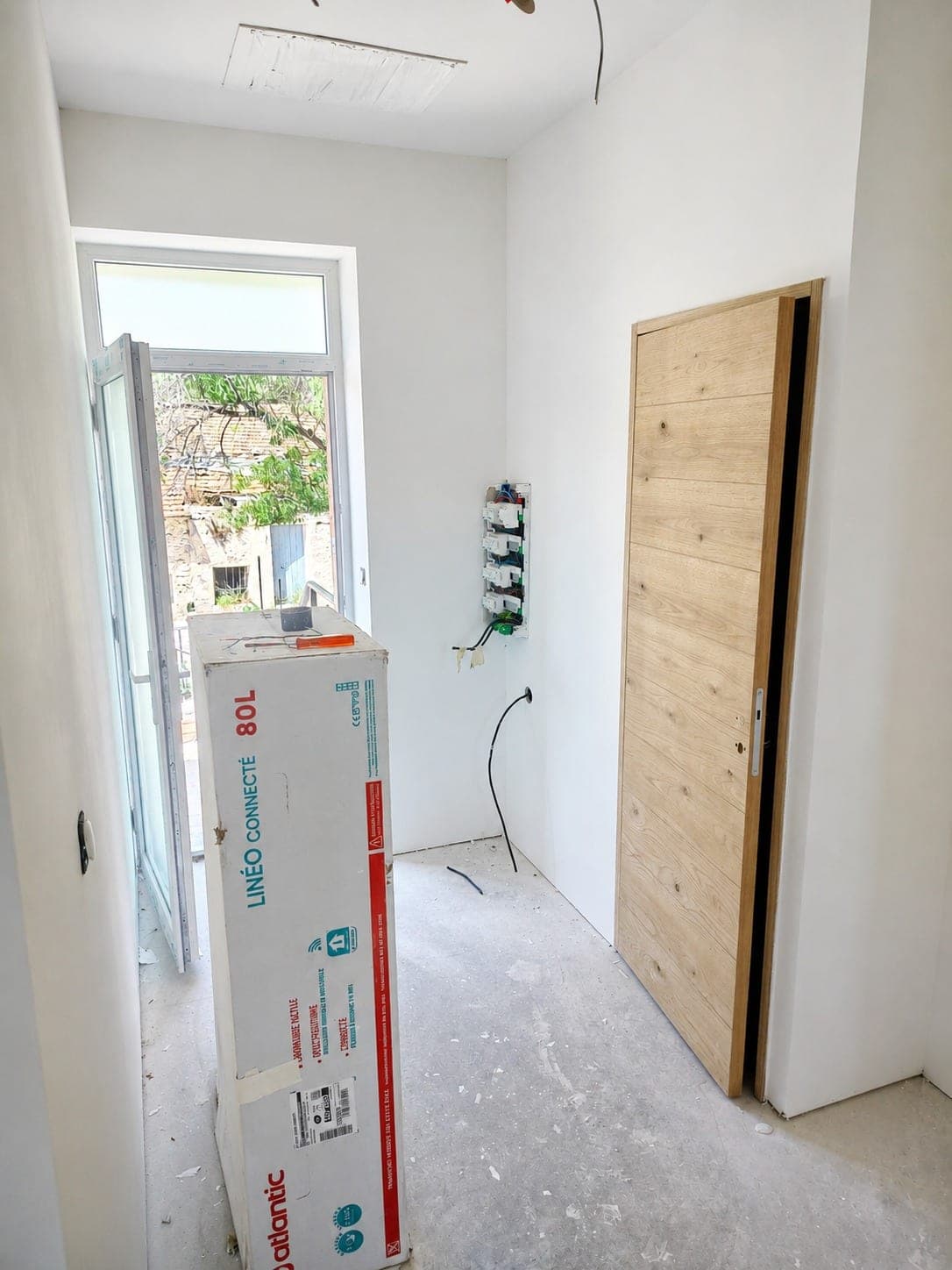 Pièce en chantier avec attentes électriques visibles au mur et au plafond.