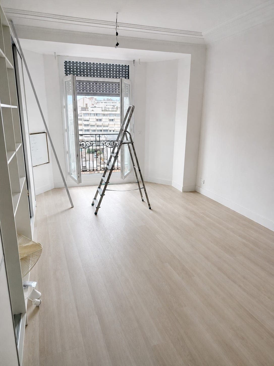 Pièce rénovée avec sol bois clair et travaux de finition en cours.