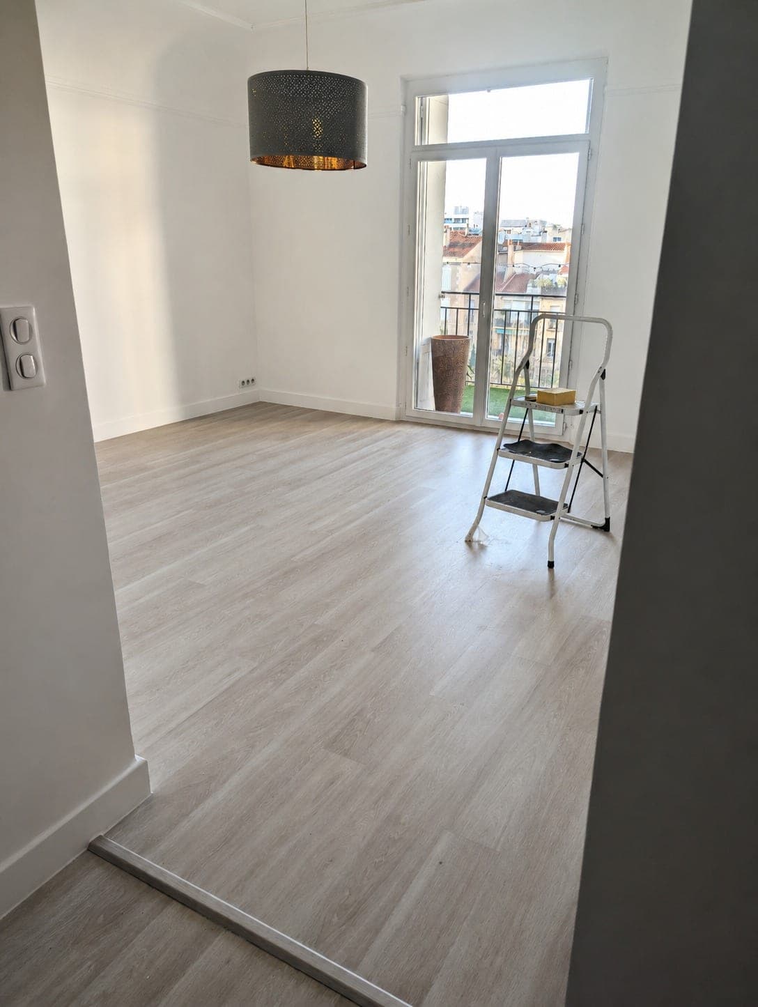 Chambre ou séjour avec sol bois clair et accès balcon.