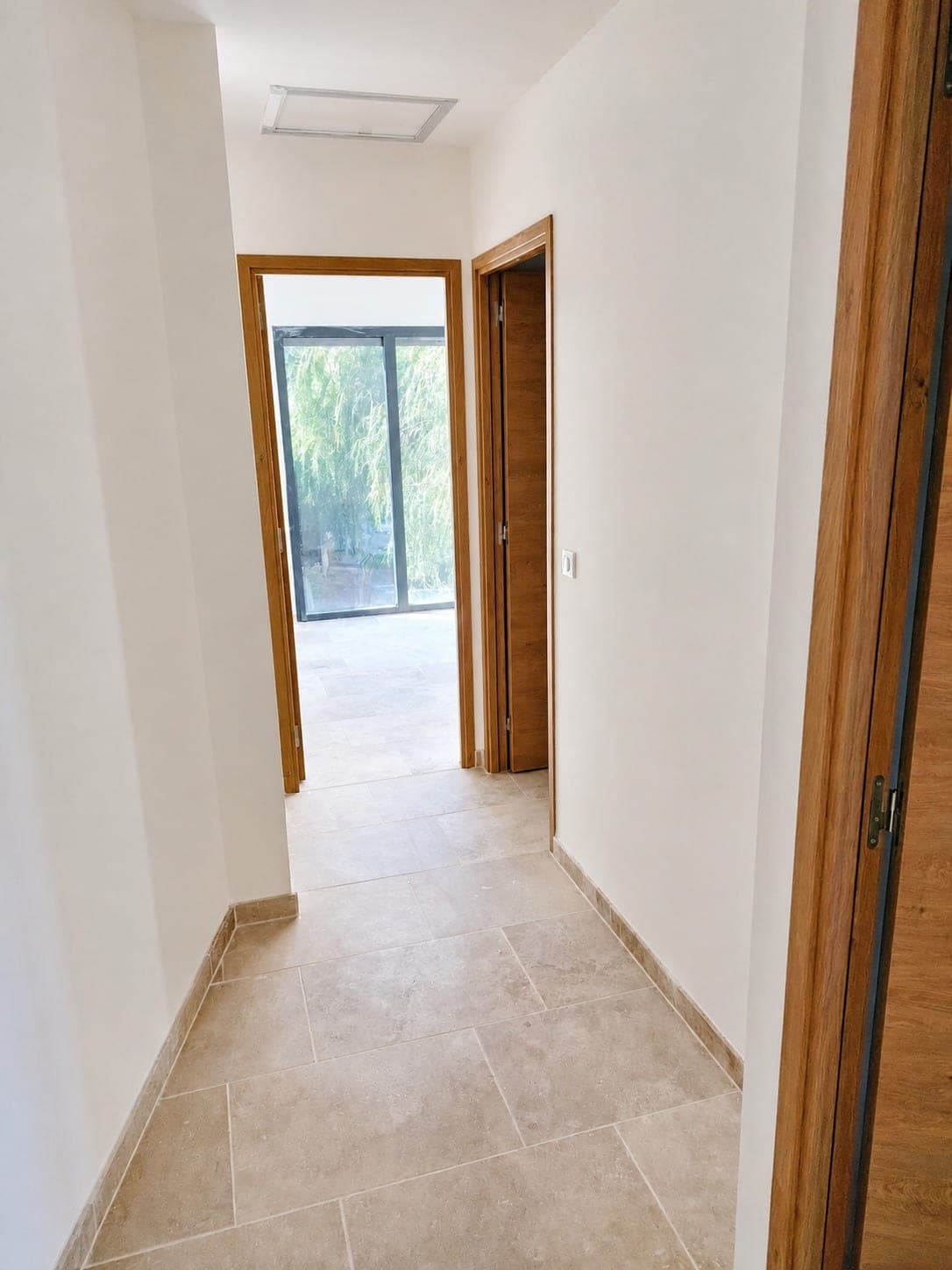 Couloir avec murs blancs repeints et menuiseries bois.