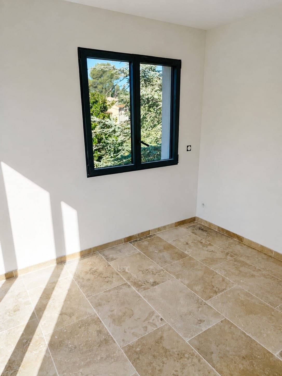 Pièce lumineuse avec murs fraîchement peints et menuiserie noire.
