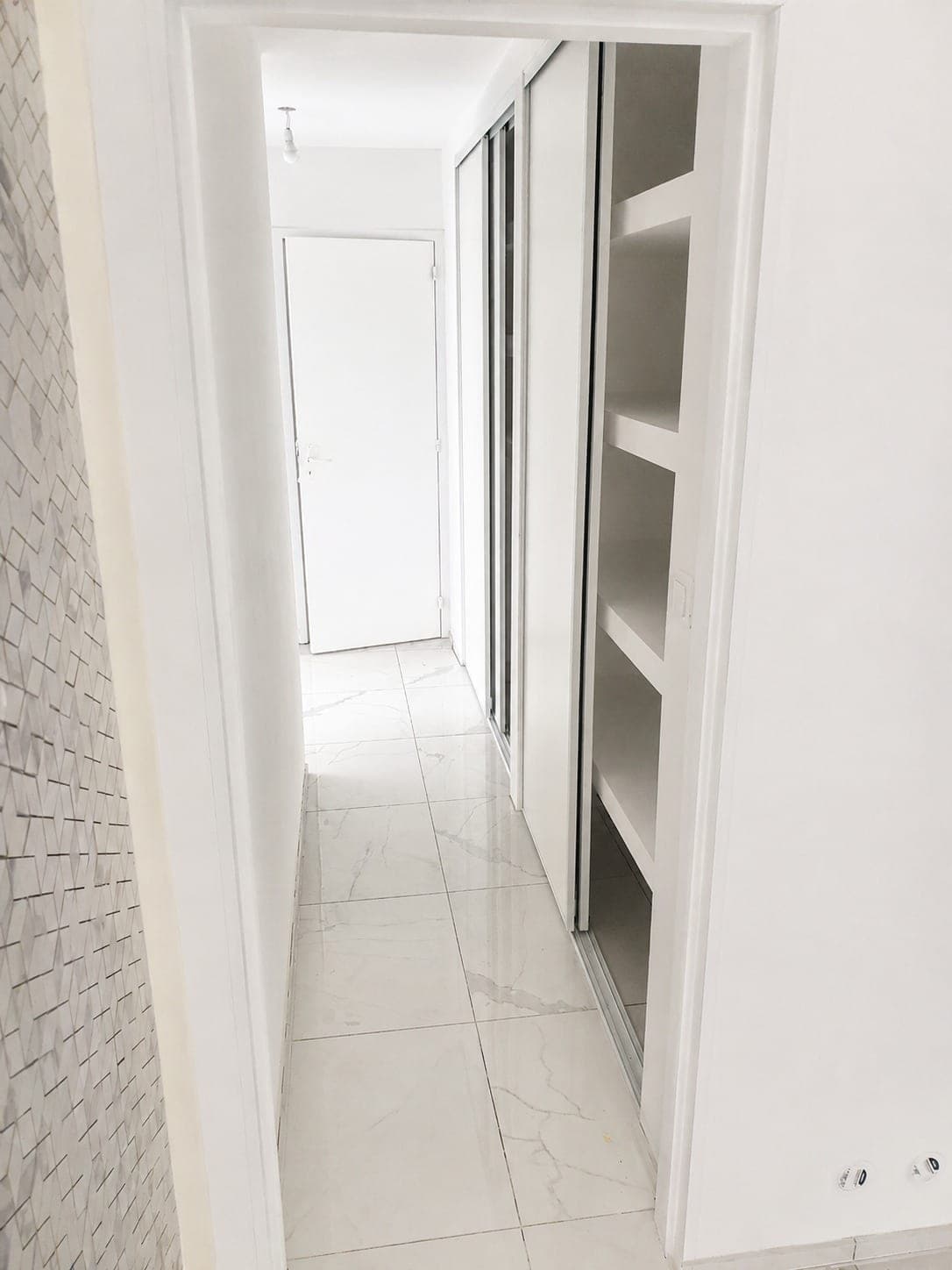 Couloir blanc avec rangements et finitions murales nettes.
