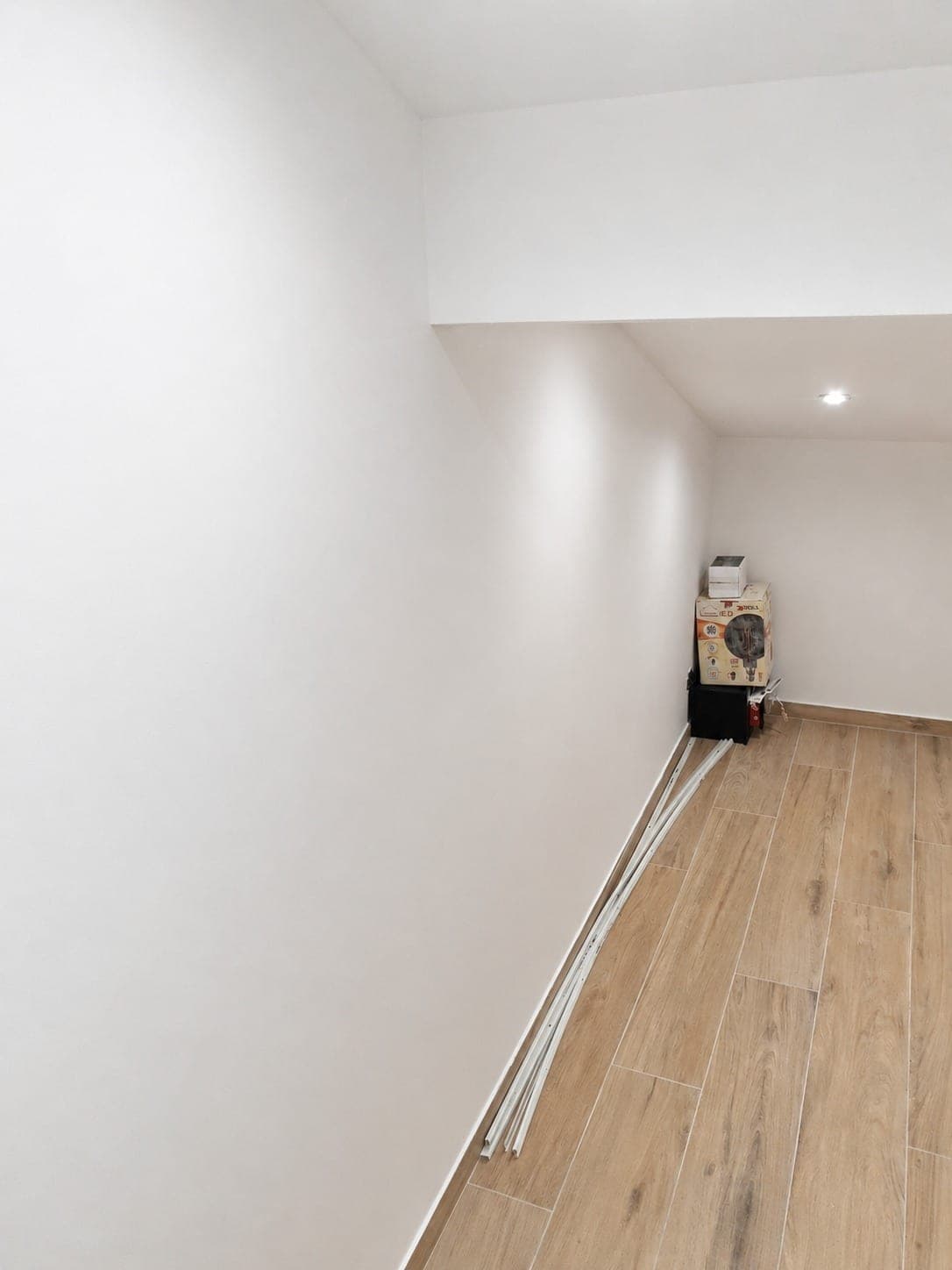 Plafond sous rampant et murs blancs finis dans une pièce mansardée.