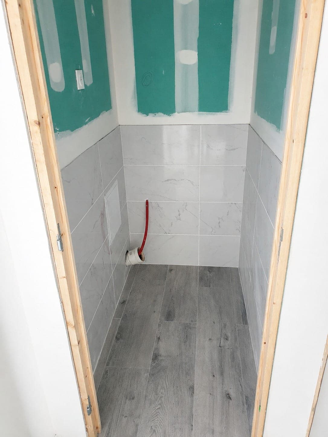 WC en chantier avec plaques, bandes et faïence partielle.