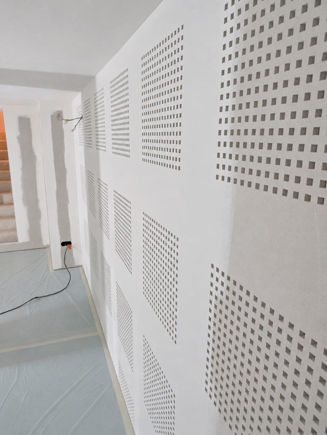 Mur ou plafond en plaques perforées avec bandes de joints.