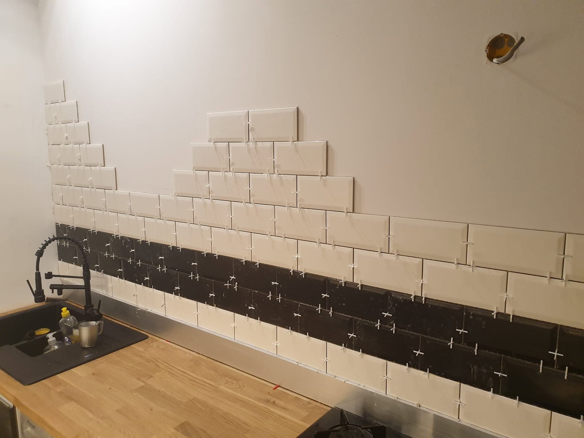 Crédence de cuisine en carreaux métro blancs avec bande noire au-dessus du plan bois