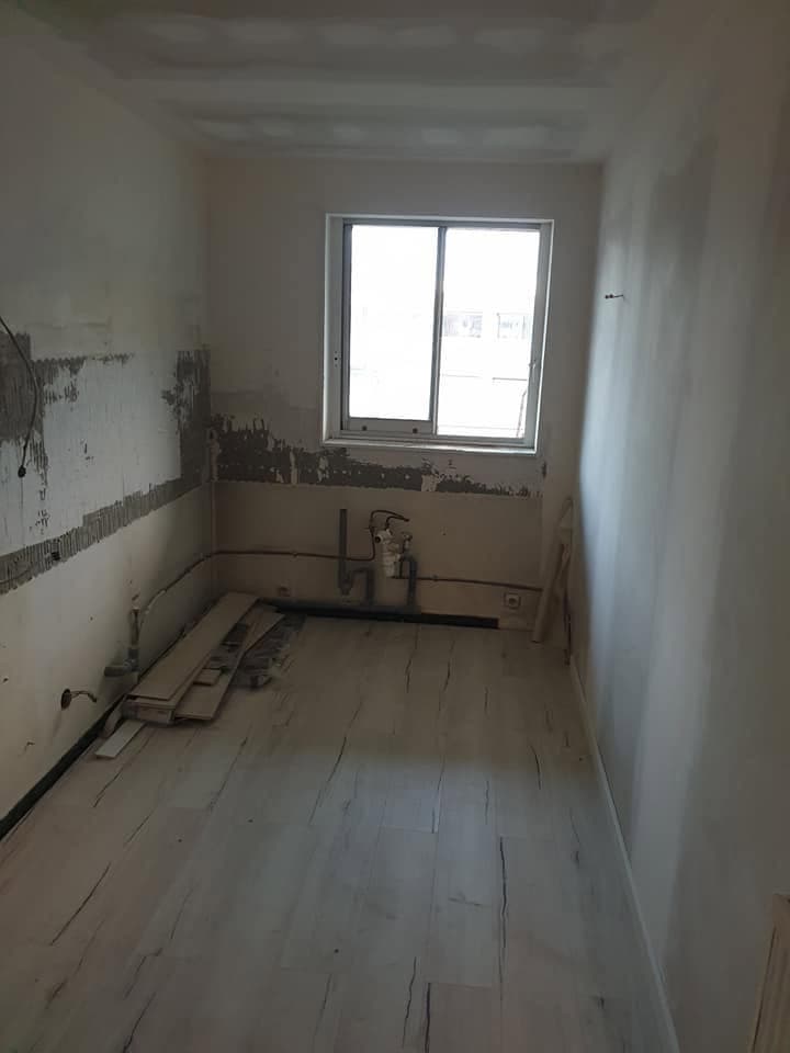 Pièce étroite en rénovation avec sol clair posé et murs enduits autour de la fenêtre