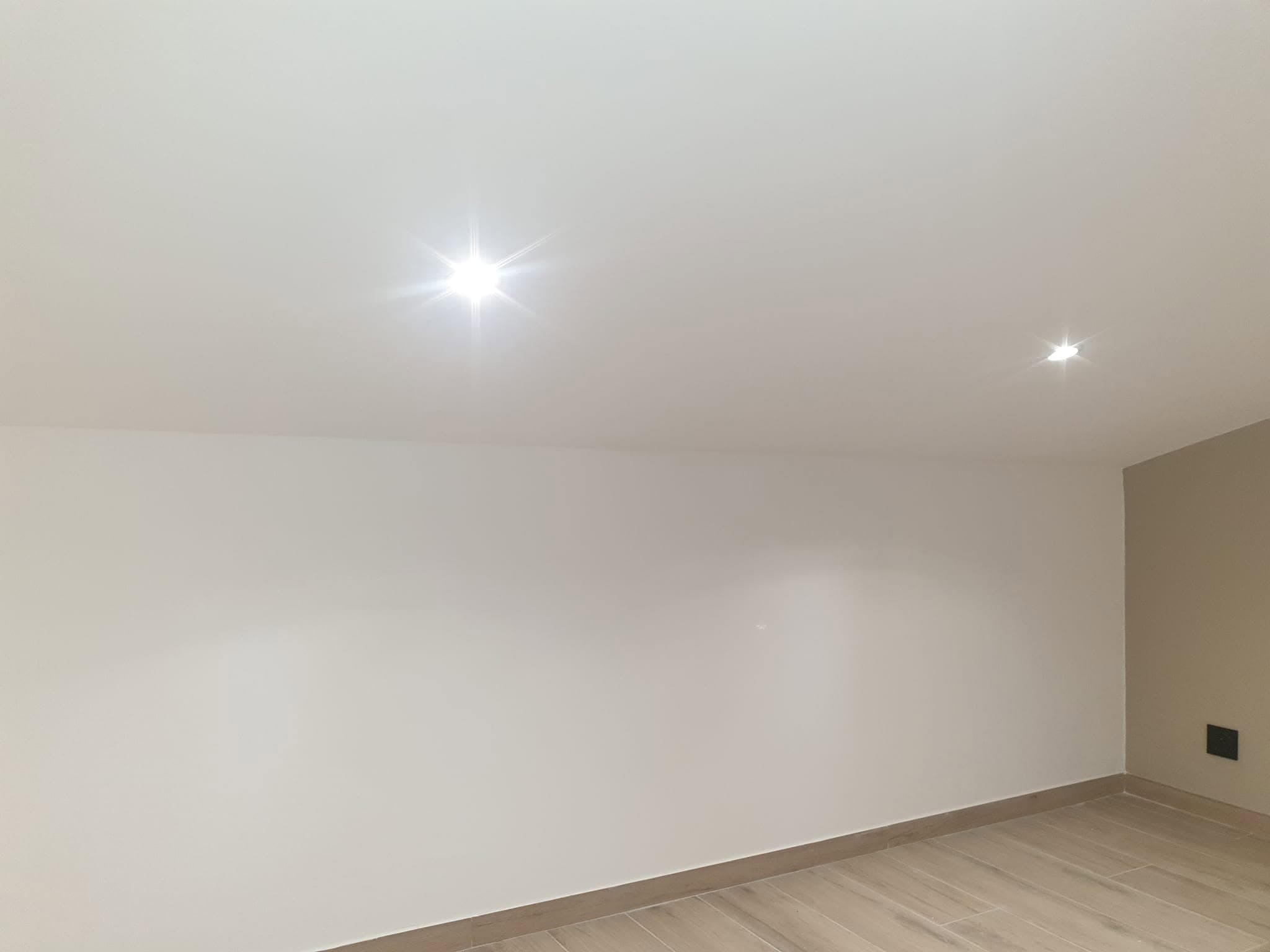 Pièce rénovée avec plafond lissé, spots encastrés et sol clair posé