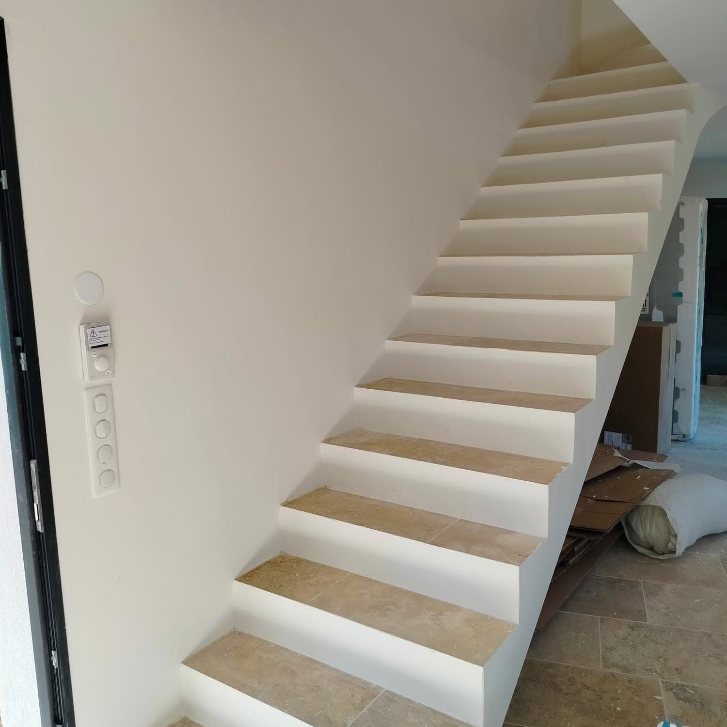 Escalier intérieur avec marches en pierre claire et murs blancs en finition