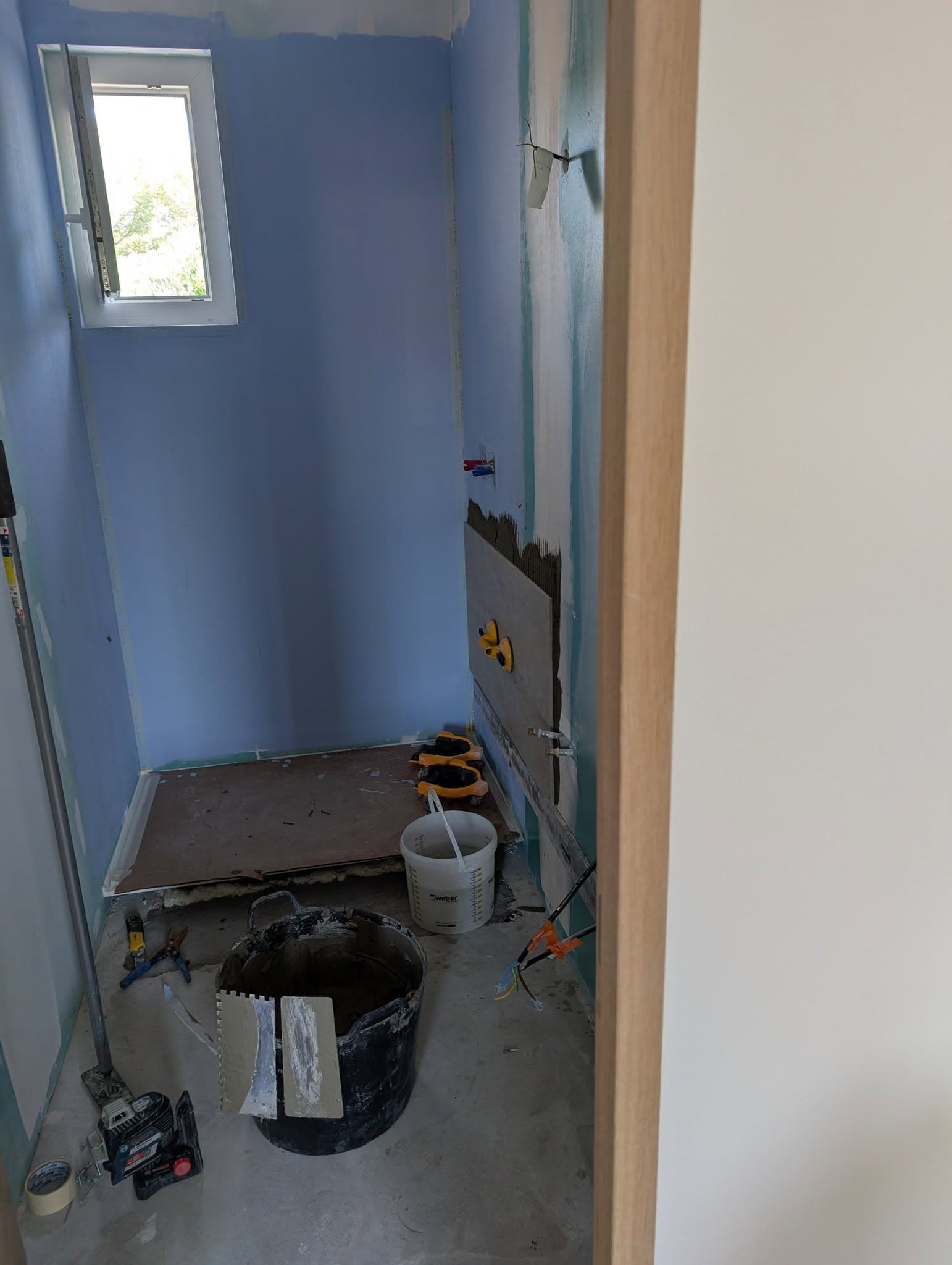Salle de bains en préparation avec étanchéité bleue avant pose du carrelage grand format