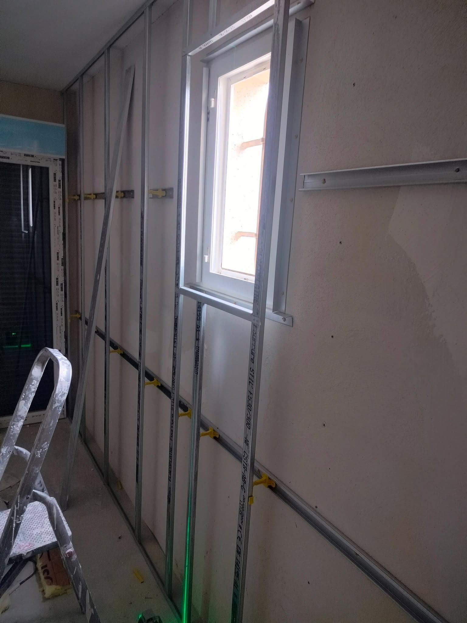 Pose de cloison et isolation autour d'une fenêtre avant fermeture et peinture