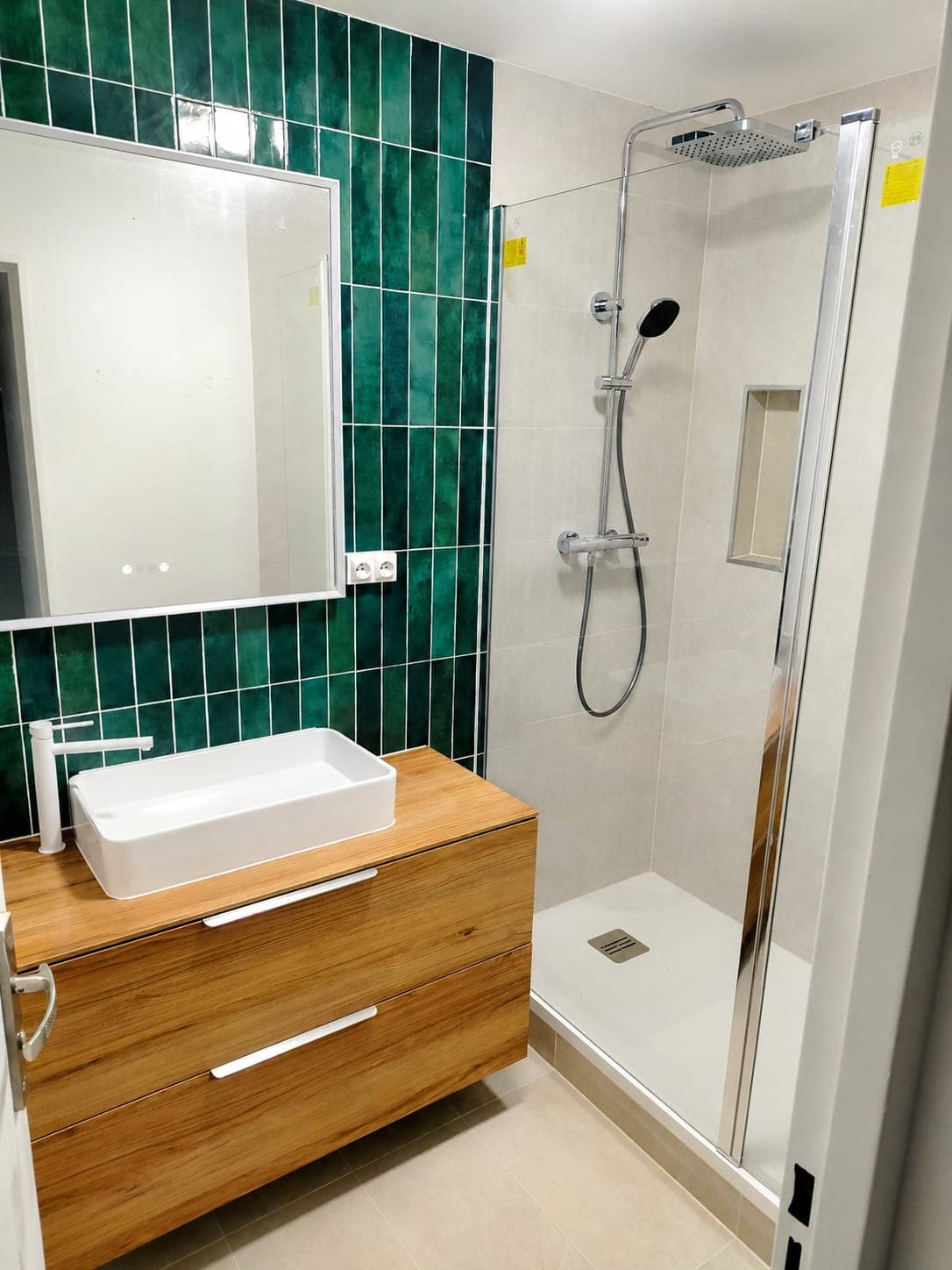 Douche, vasque et robinetterie dans une salle d'eau rénovée.